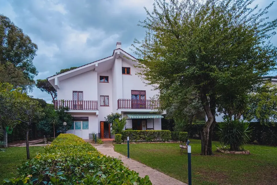 Villa Flora vista dal giardino: la villa bianca a due piani con balconi, siepi e vialetto