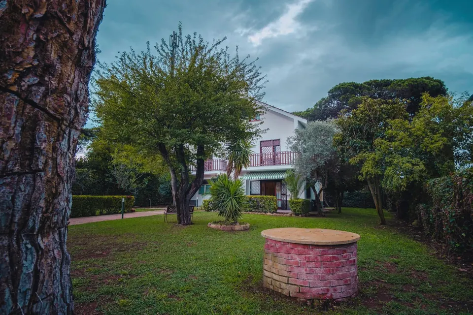 Il giardino di Villa Flora con alberi, prato e un pozzo in mattoni